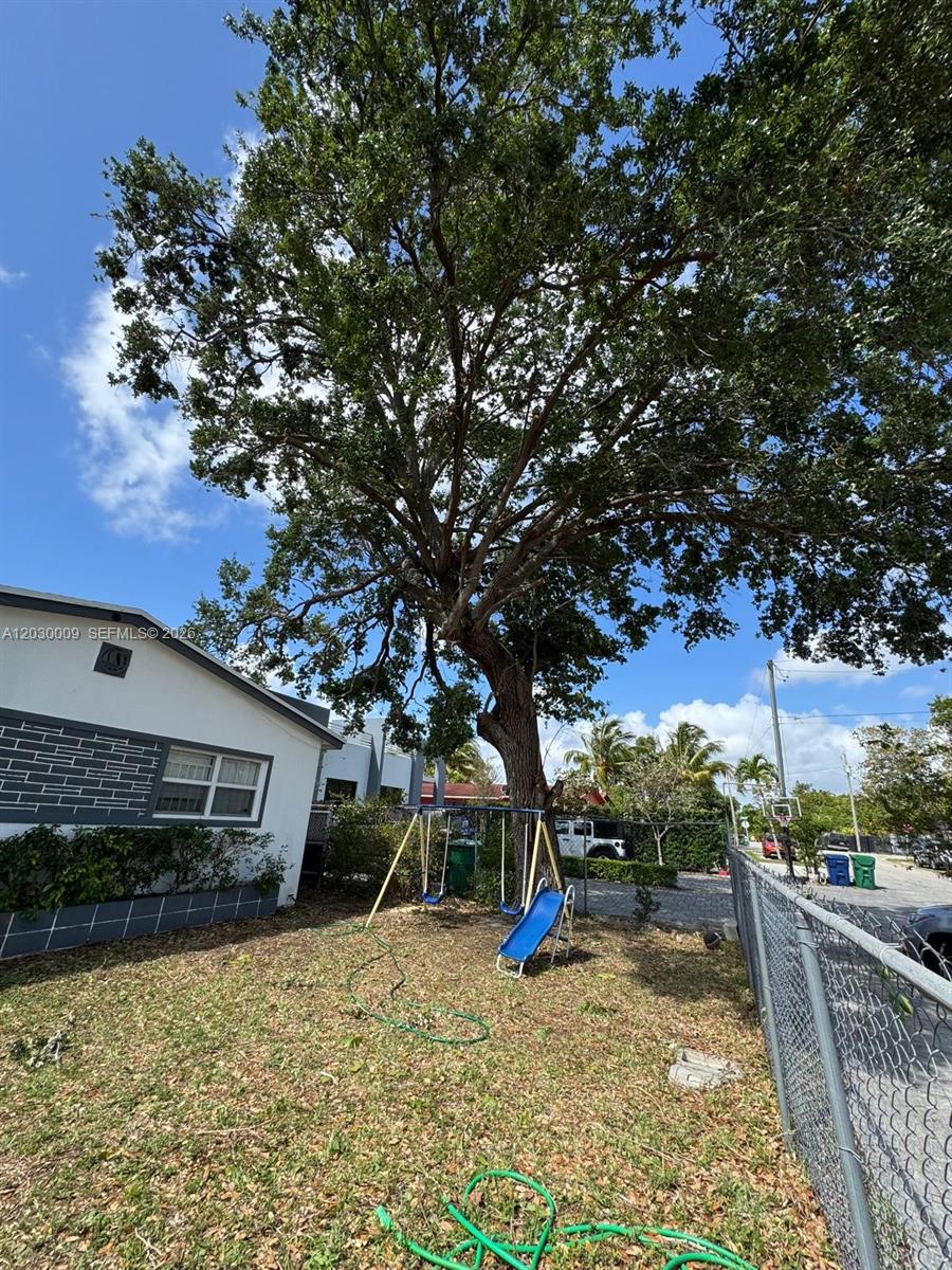 A large tree stands in a backyard next to a house with a swing set — 1226 NE 112th St # 1226, Miami FL 33161, MIAMI, FL