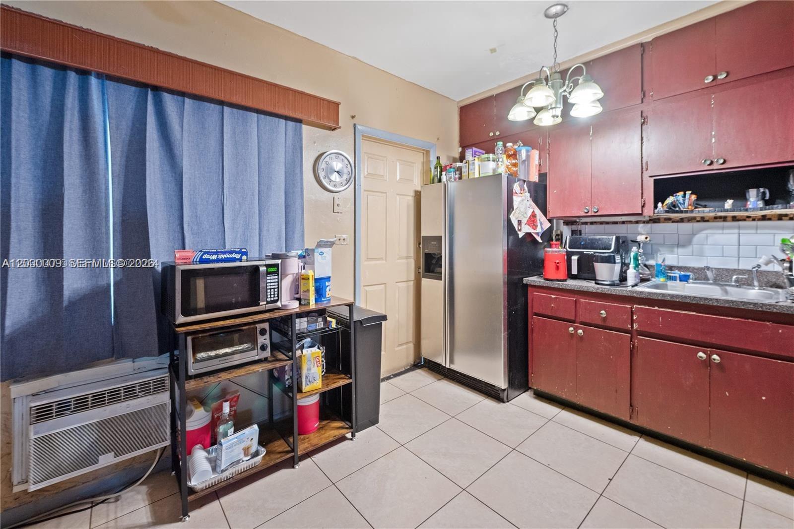 This kitchen features red cabinets, a stainless steel refrigerator, and a metal shelving unit — 1226 NE 112th St # 1226, Miami FL 33161, MIAMI, FL