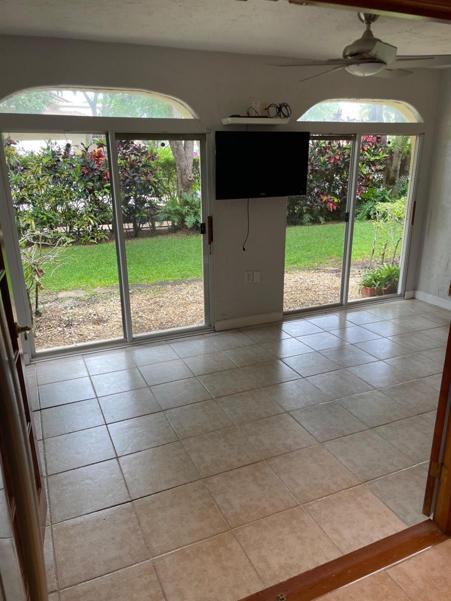 A bathroom features a black vanity with a white countertop, a silver-framed mirror, and wood door — 6654 Via Regina, Boca Raton FL 33433, BOCA RATON, FL