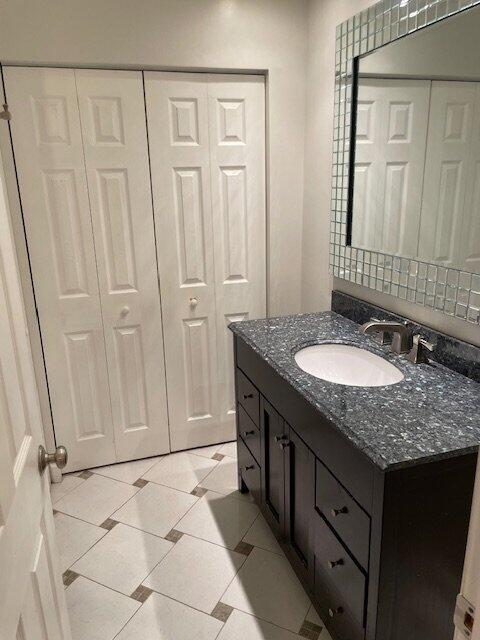 A bathroom vanity with a white countertop and silver-framed mirror sits beside a doorway — 6654 Via Regina, Boca Raton FL 33433, BOCA RATON, FL