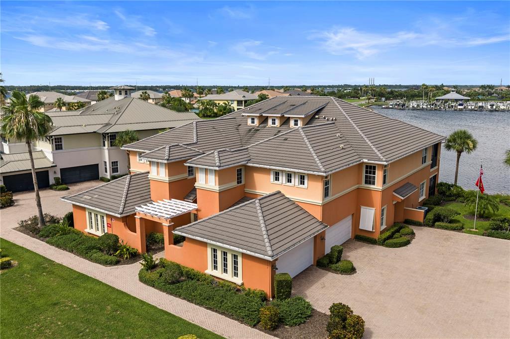 An aerial view of a multi-story orange stucco house with a tiled roof near water — 1139 RIVERSCAPE STREET UNIT 2, BRADENTON, FL
