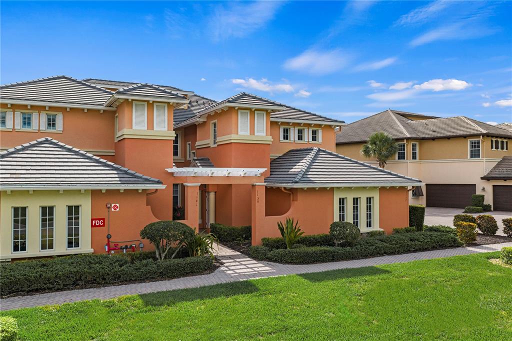 An exterior view of a two-story orange stucco building with a tiled roof and walkway — 1139 RIVERSCAPE STREET UNIT 2, BRADENTON, FL