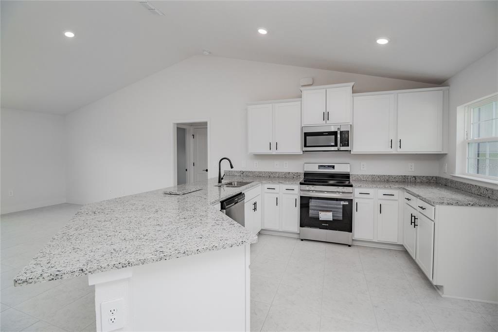 A kitchen with white cabinets, granite countertops, stainless steel appliances, and a large island — 1218 HICKORY NUT DRIVE, LAKE WALES, FL