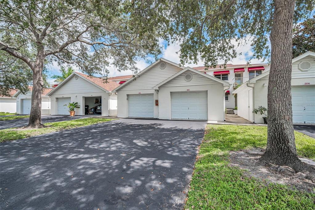 The exterior of a residential building featuring multiple garage doors and a paved driveway — 1400 WATER VIEW DRIVE W UNIT 104, LARGO, FL