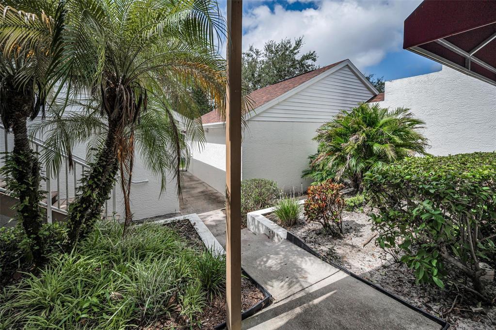 An outdoor walkway leads between two white buildings with palm trees and landscaping — 1400 WATER VIEW DRIVE W UNIT 104, LARGO, FL