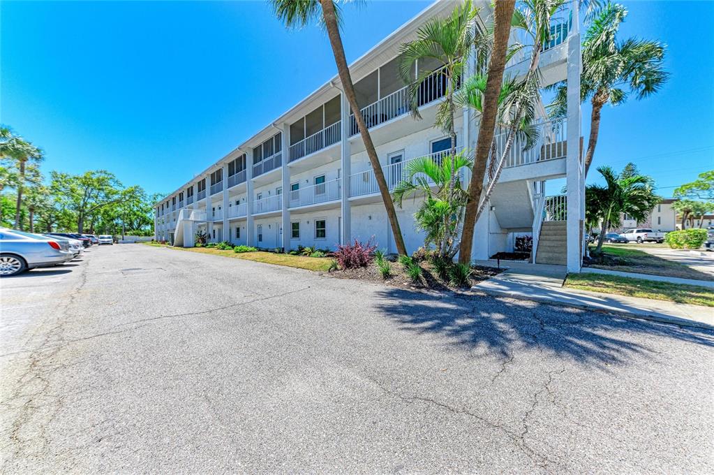 A three-story white apartment building with screened balconies and palm trees in a parking lot — 4920 38TH WAY S UNIT 210, ST PETERSBURG, FL