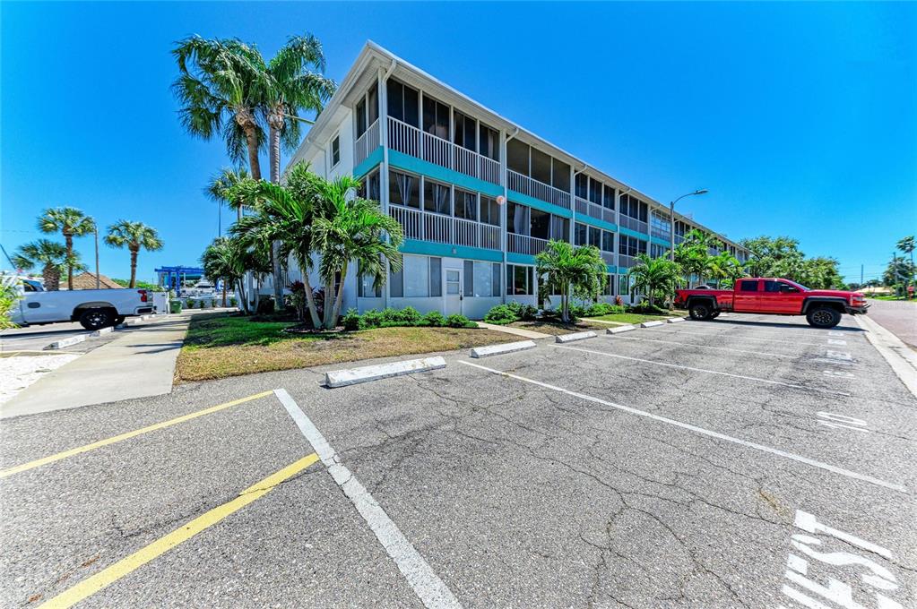 A three-story apartment building with screened balconies sits next to a parking lot — 4920 38TH WAY S UNIT 210, ST PETERSBURG, FL
