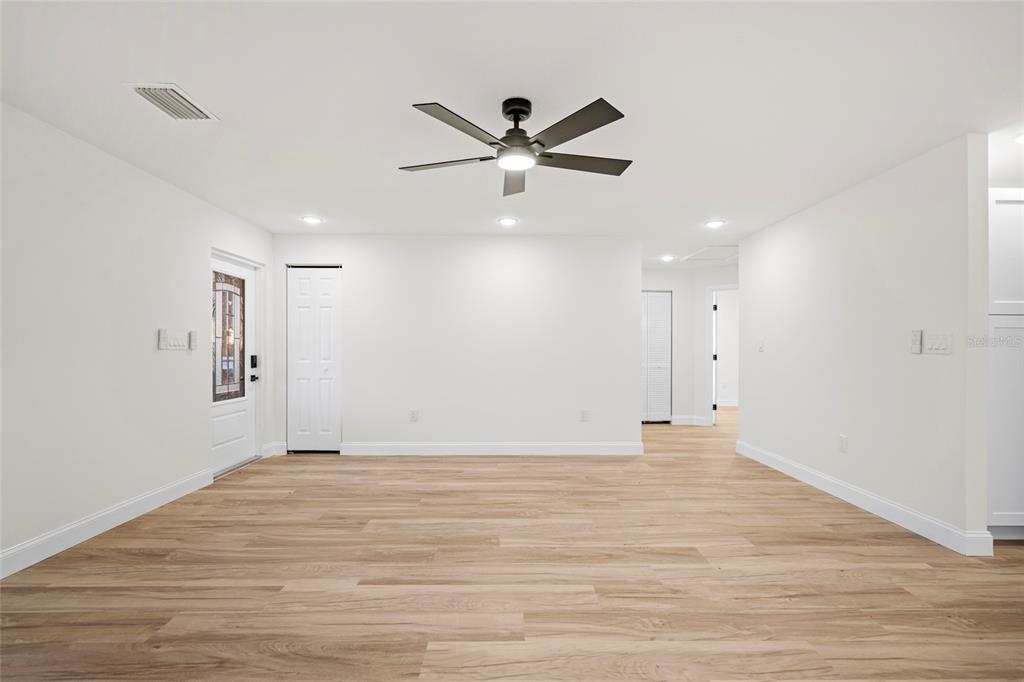 A bright, open-concept living area features light wood-look flooring, white walls, and a ceiling fan — 19570 NW 290TH STREET, OKEECHOBEE, FL