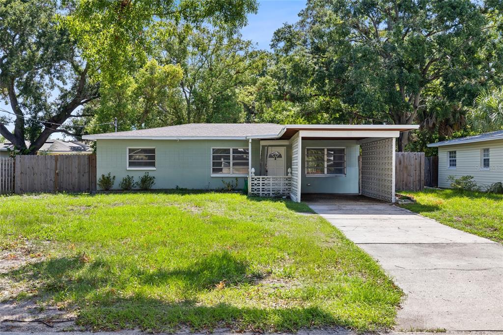 A single-story house with light green siding, a concrete driveway, and an attached carport — 206 N GUNLOCK AVENUE, TAMPA, FL
