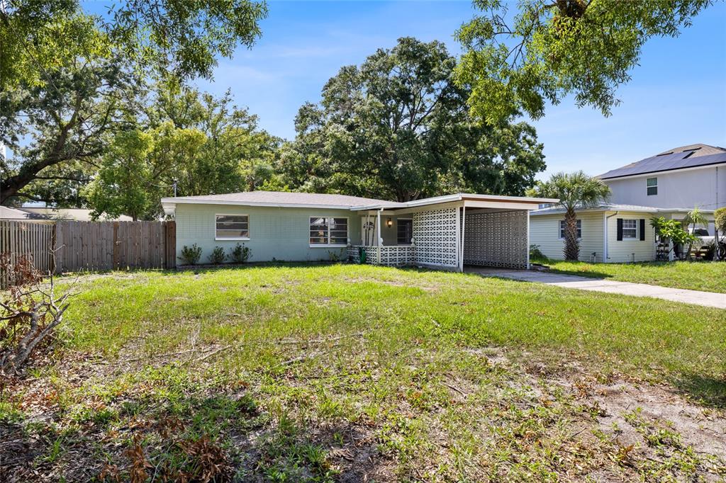 A single-story house with a light green exterior, a carport, and a large front yard — 206 N GUNLOCK AVENUE, TAMPA, FL