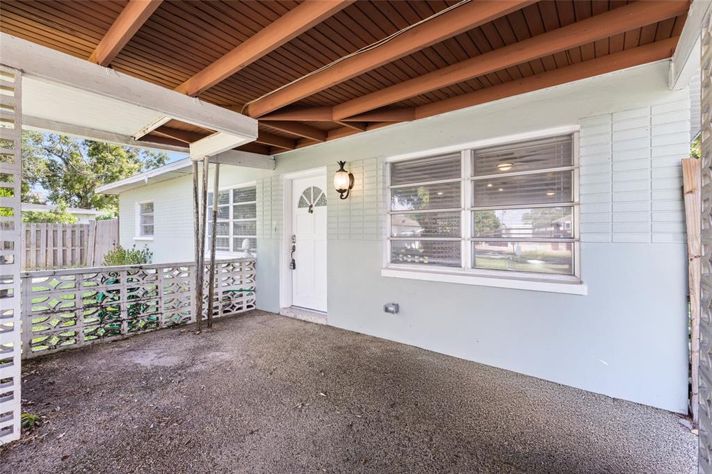 A covered concrete porch with a white front door and decorative breeze block railing — 206 N GUNLOCK AVENUE, TAMPA, FL