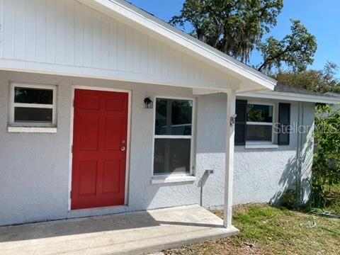 A light gray house exterior features a bright red front door and a concrete porch — 110 KARDE LANE, BRANDON, FL