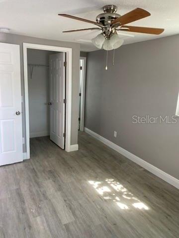 A bedroom with gray walls, light wood-look flooring, and a ceiling fan with lights — 110 KARDE LANE, BRANDON, FL