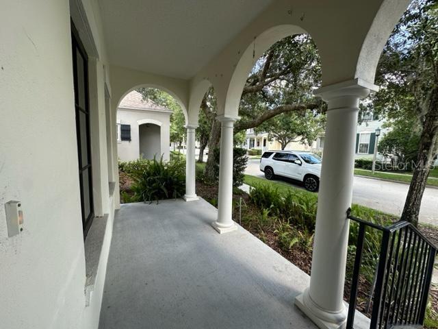 A covered porch features white columns, arched openings, and a concrete floor overlooking a street — 906 PAWSTAND ROAD, CELEBRATION, FL