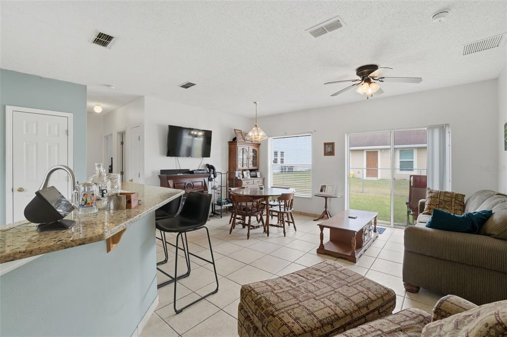 An open-concept living and dining area features tile flooring, a kitchen island, and sliding doors — 354 DUNDEE DRIVE, KISSIMMEE, FL