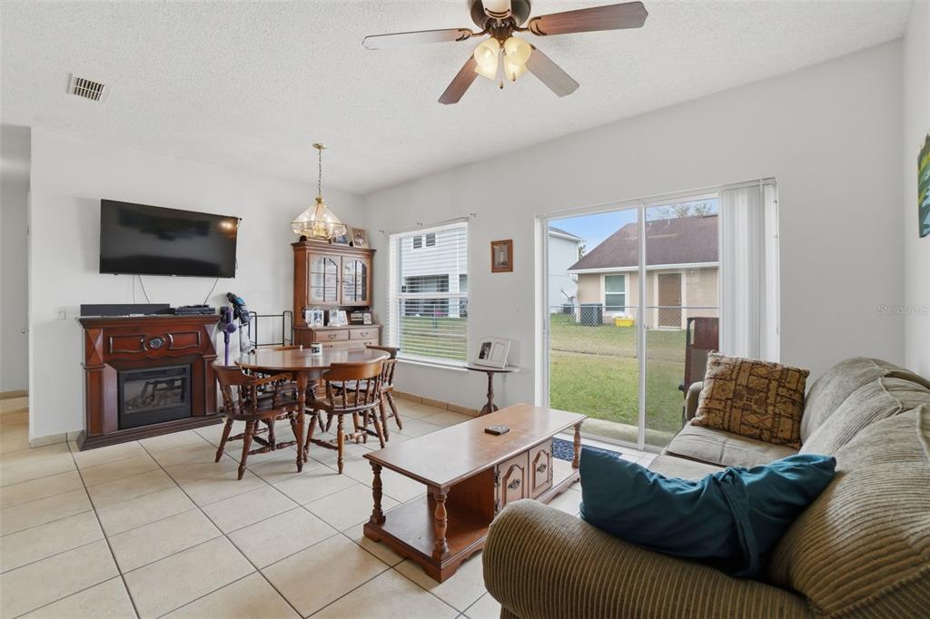 A living and dining area features tile flooring, a ceiling fan, and a sliding glass door — 354 DUNDEE DRIVE, KISSIMMEE, FL