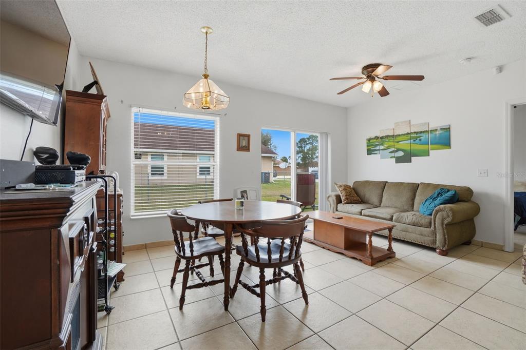 A living and dining area features tile floors, a wooden table, and a brown sofa — 354 DUNDEE DRIVE, KISSIMMEE, FL