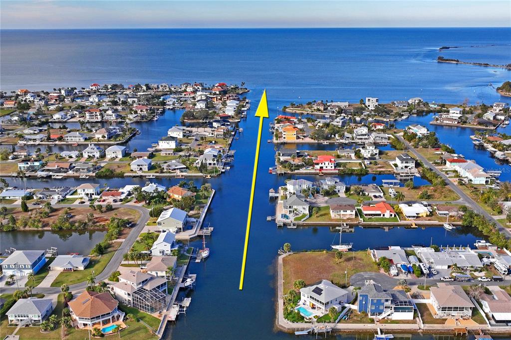 An aerial view shows waterfront homes lining a canal leading out to the open sea — Lot 8 6TH ISLE, HERNANDO BEACH, FL