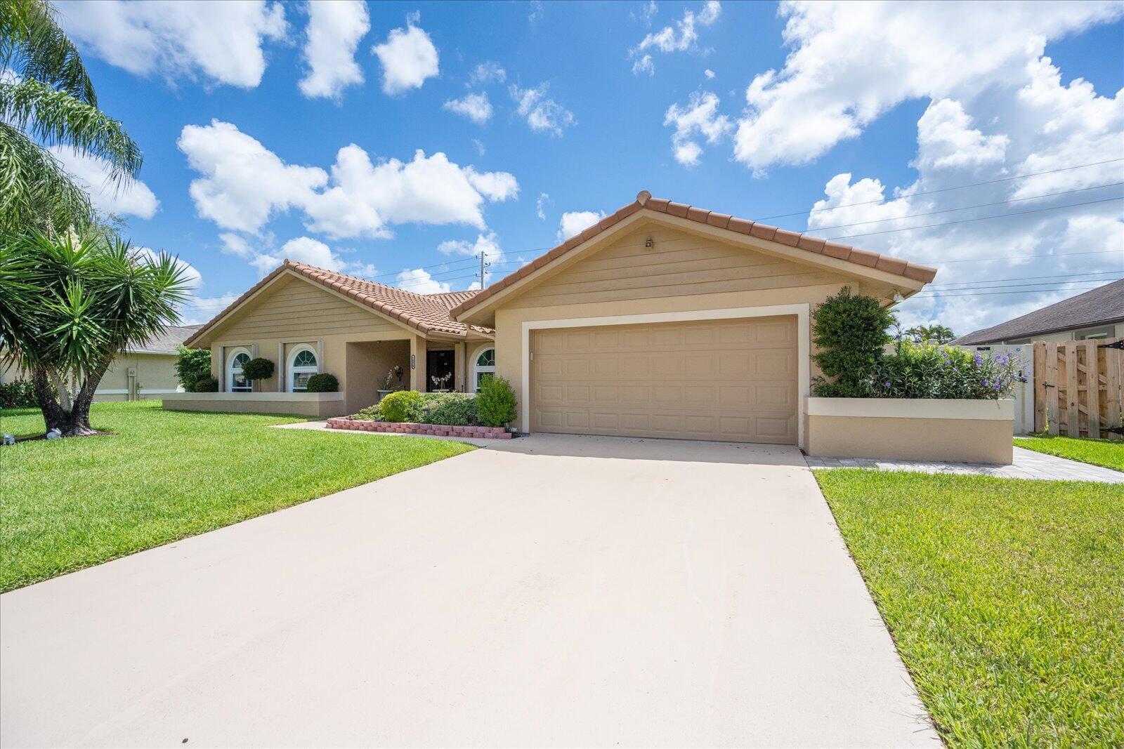 A single-story house with a tan exterior, a two-car garage, and a concrete driveway — 1654 Farmington Circle, Wellington FL 33414, WELLINGTON, FL