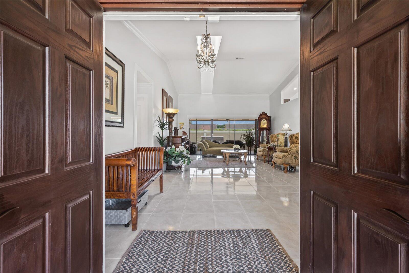 A view through double doors into a tiled foyer leading to a spacious living area — 1654 Farmington Circle, Wellington FL 33414, WELLINGTON, FL