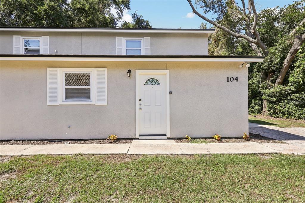 The exterior of a two-story building features a white front door and a single window — 104 HALLMARK COURT, LAKE MARY, FL