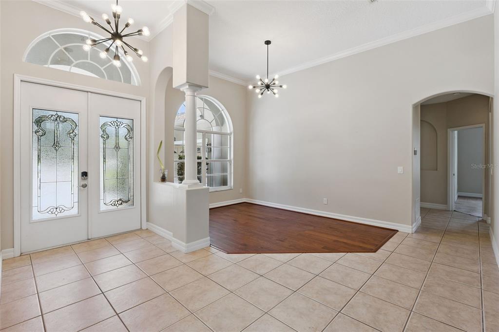 An entryway with tile flooring, a wood-floored dining area, and two modern sputnik chandeliers — 1353 BRIDGE HILL LANE, CLERMONT, FL