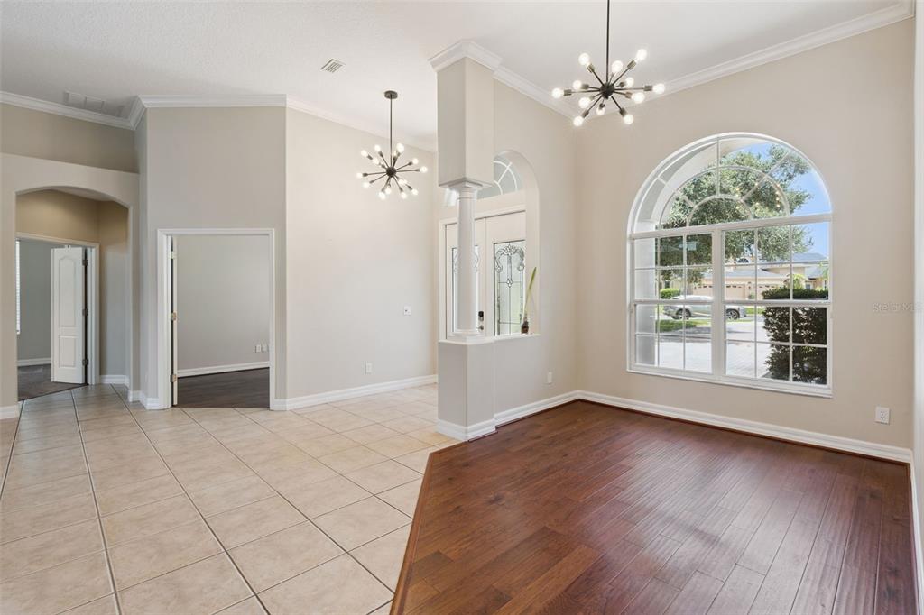 A room with tile and wood flooring, a large arched window, and two sputnik chandeliers — 1353 BRIDGE HILL LANE, CLERMONT, FL