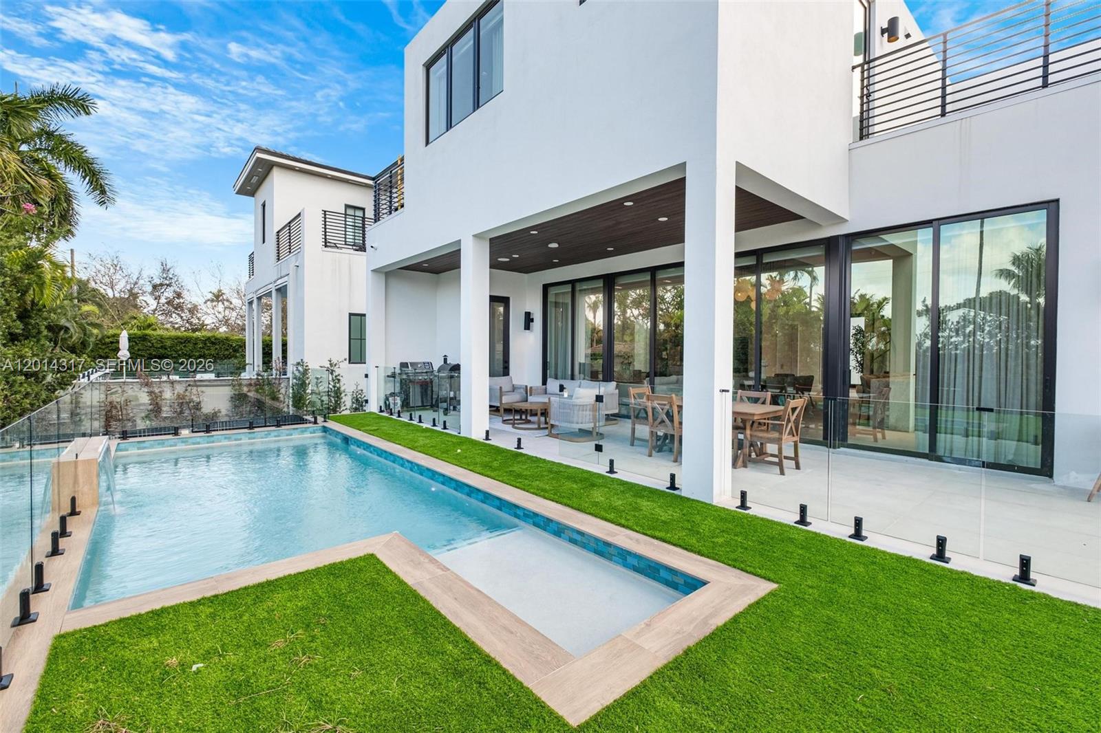 A modern white house features a swimming pool, artificial turf, and a covered patio area — 9280 Byron Ave, Surfside FL 33154, SURFSIDE, FL