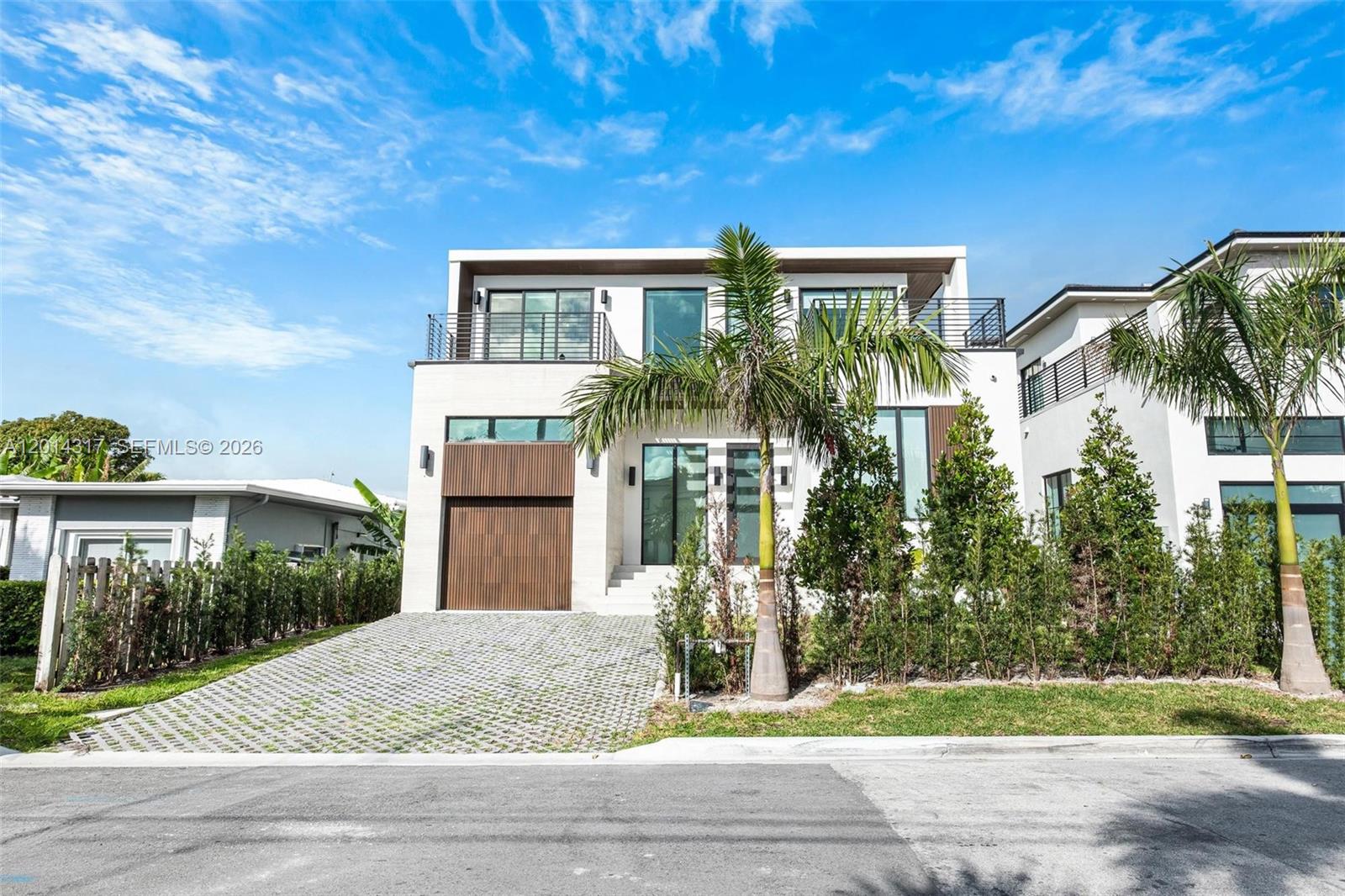 A modern two-story house features a slatted wood garage door and a paved driveway — 9280 Byron Ave, Surfside FL 33154, SURFSIDE, FL