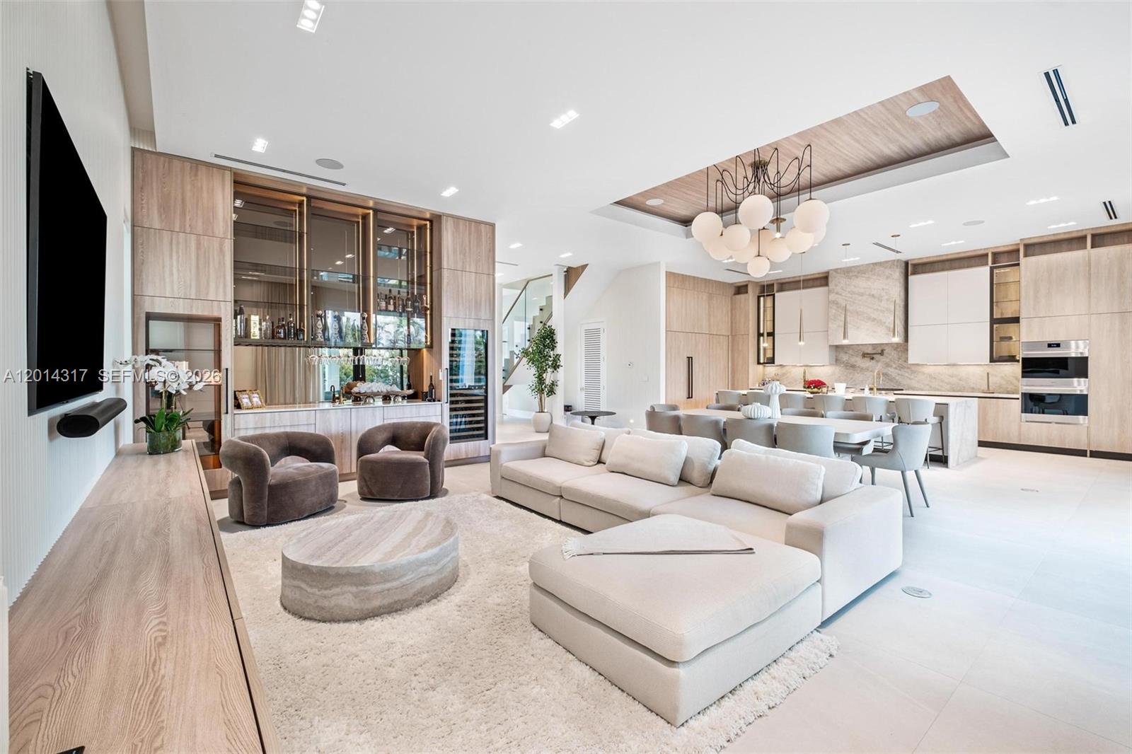 A modern open-concept living room features a large sectional sofa, a bar area, and kitchen — 9280 Byron Ave, Surfside FL 33154, SURFSIDE, FL