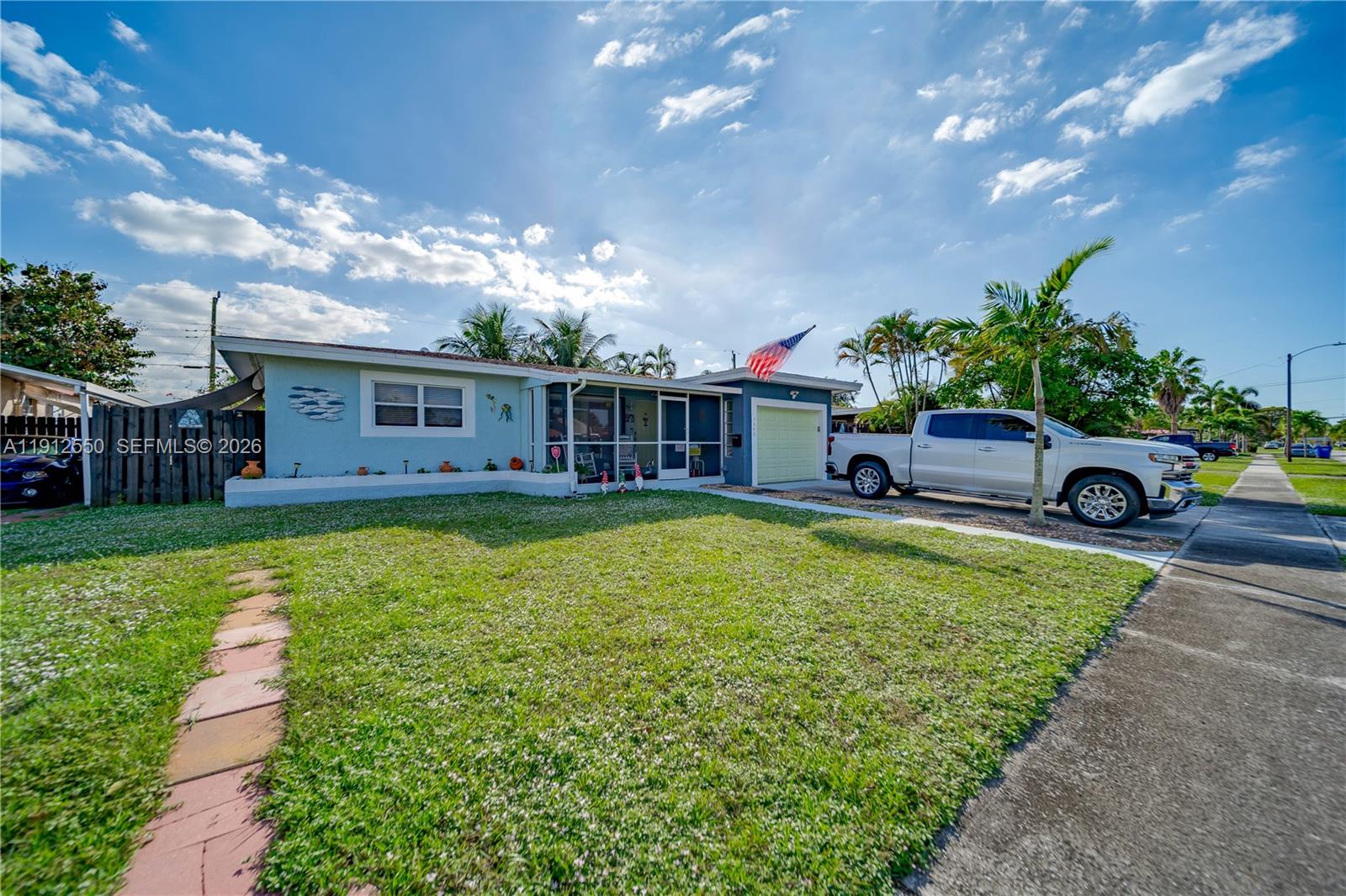 A screened-in porch features two white rocking chairs, a large window, and a front door — 7440 Fillmore St, Hollywood FL 33024, HOLLYWOOD, FL