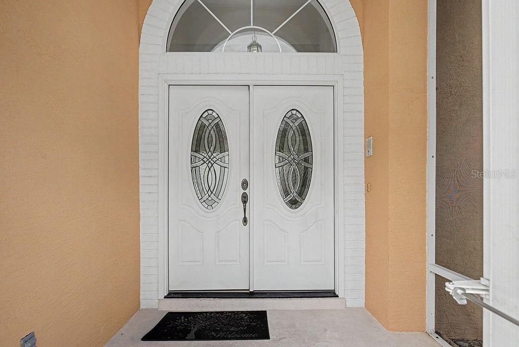 A white double front door with oval glass inserts sits under an arched transom window — 20811 SW 81ST LOOP, DUNNELLON, FL