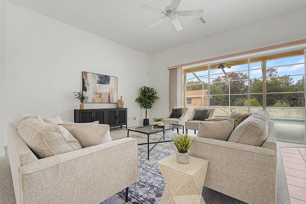 A living room features two beige sofas, a glass coffee table, and large sliding glass doors — 20811 SW 81ST LOOP, DUNNELLON, FL