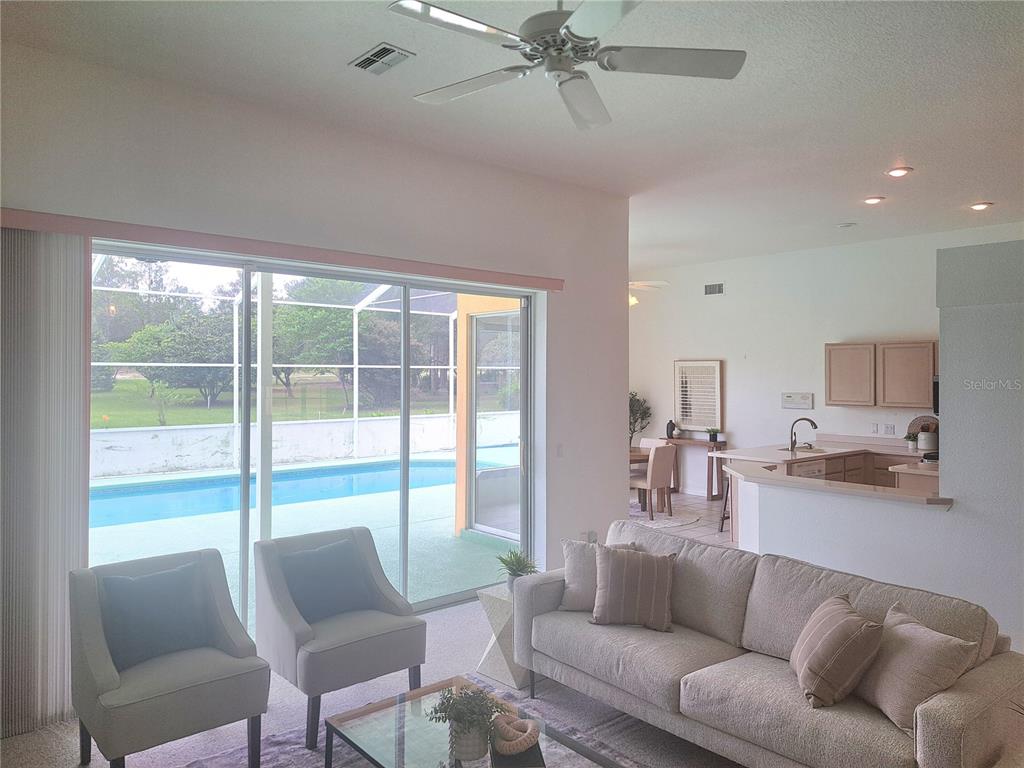 A living room with a sofa and chairs overlooks a patio with a swimming pool — 20811 SW 81ST LOOP, DUNNELLON, FL
