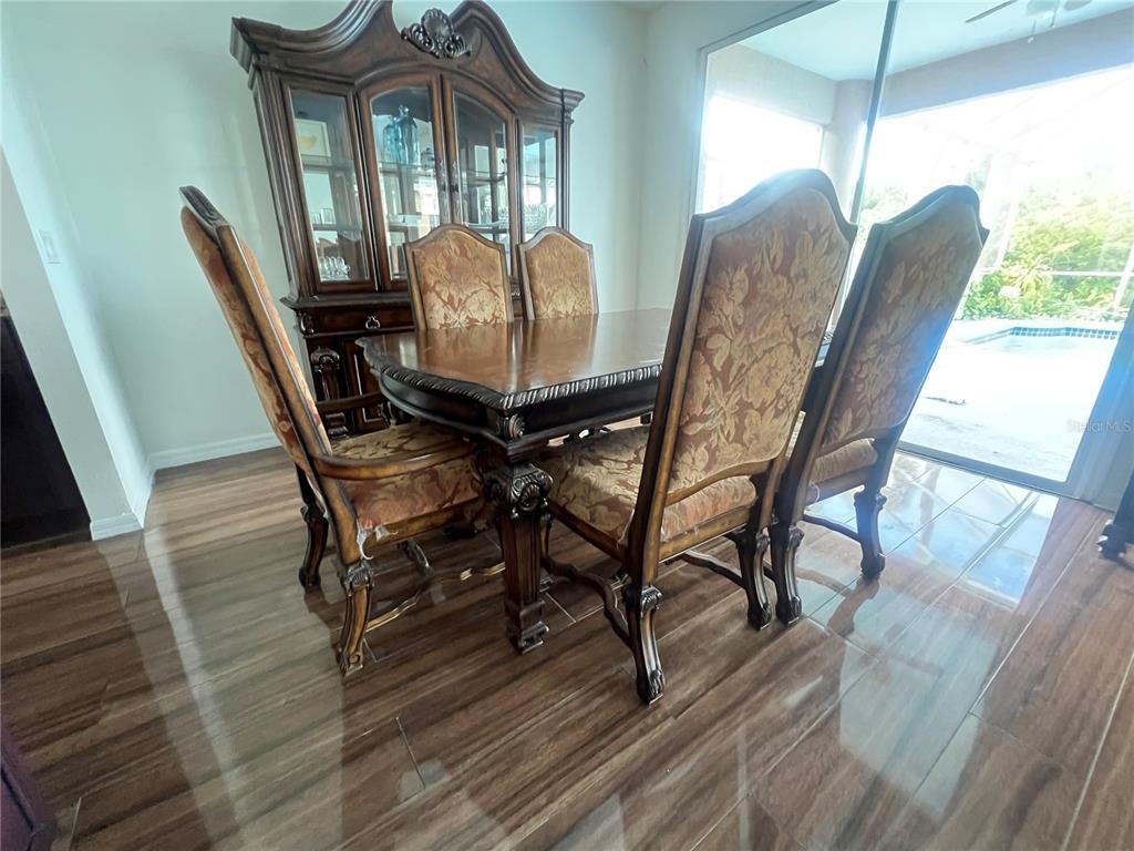 A dining room features a wooden table, upholstered chairs, a large hutch, and tile flooring — 6222 LAUREL CREEK TRAIL, ELLENTON, FL