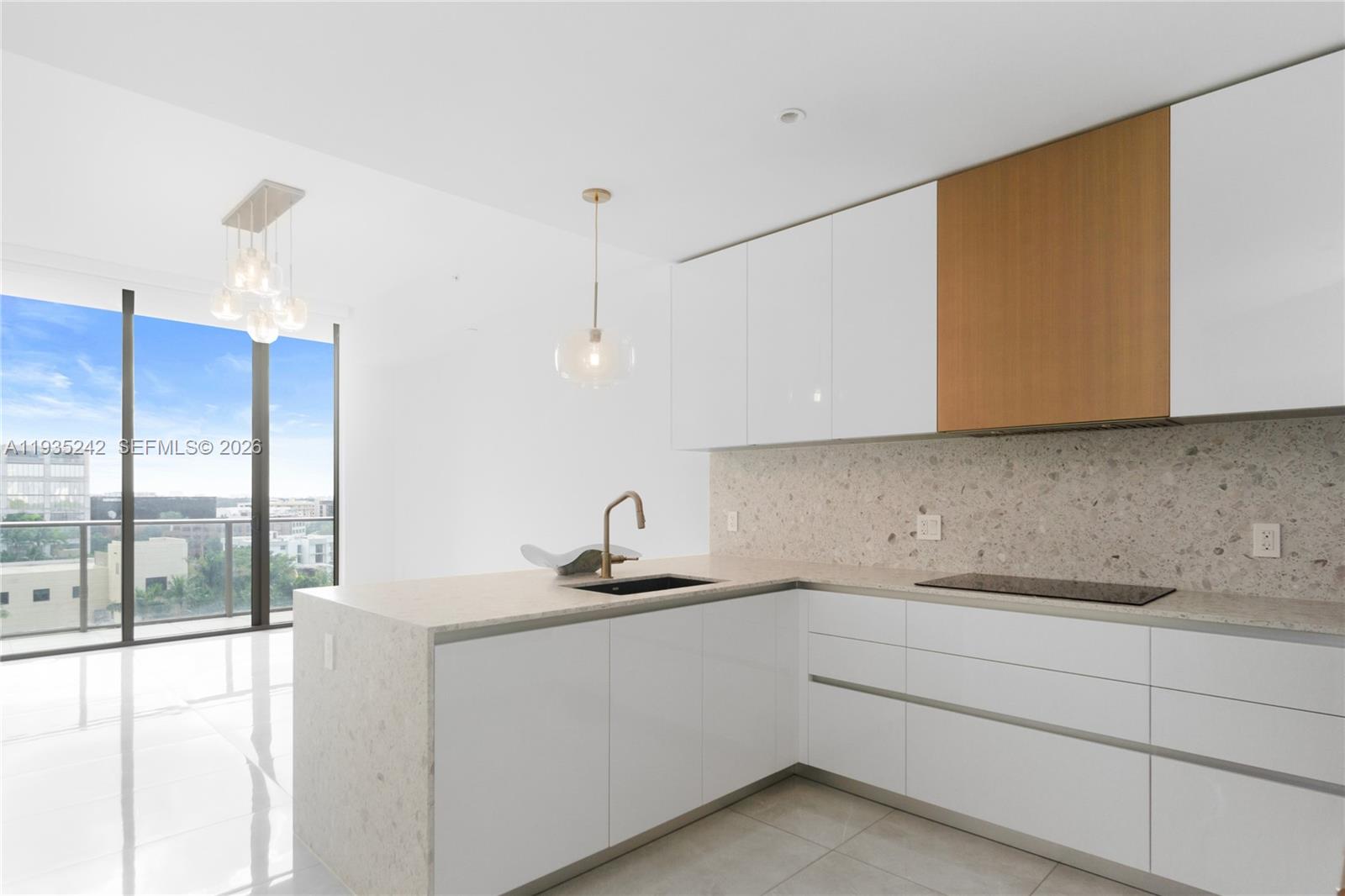 A modern kitchen features white cabinets, wood accents, a stone backsplash, and a large island — 2678 Tigertail Ave # 715, Miami FL 33133, MIAMI, FL
