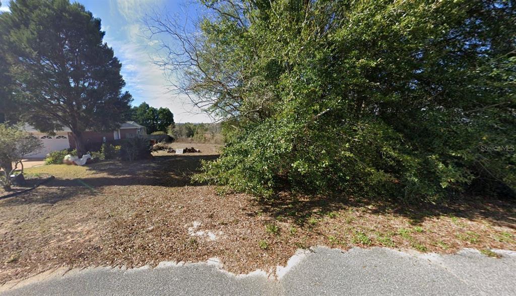 A vacant, wooded residential lot sits next to a house with a garage — 921 MARACEL LOOP, CRESTVIEW, FL