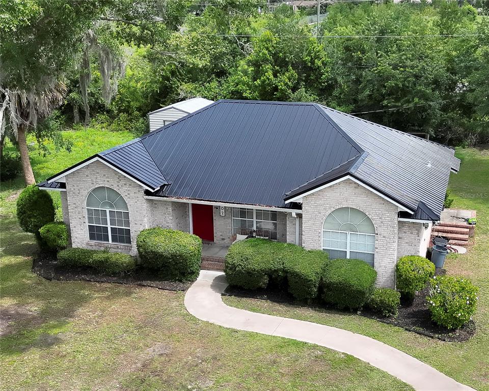 An aerial view of a single-story brick house with a dark metal roof — 1302 MAYRA ROAD SW, LIVE OAK, FL