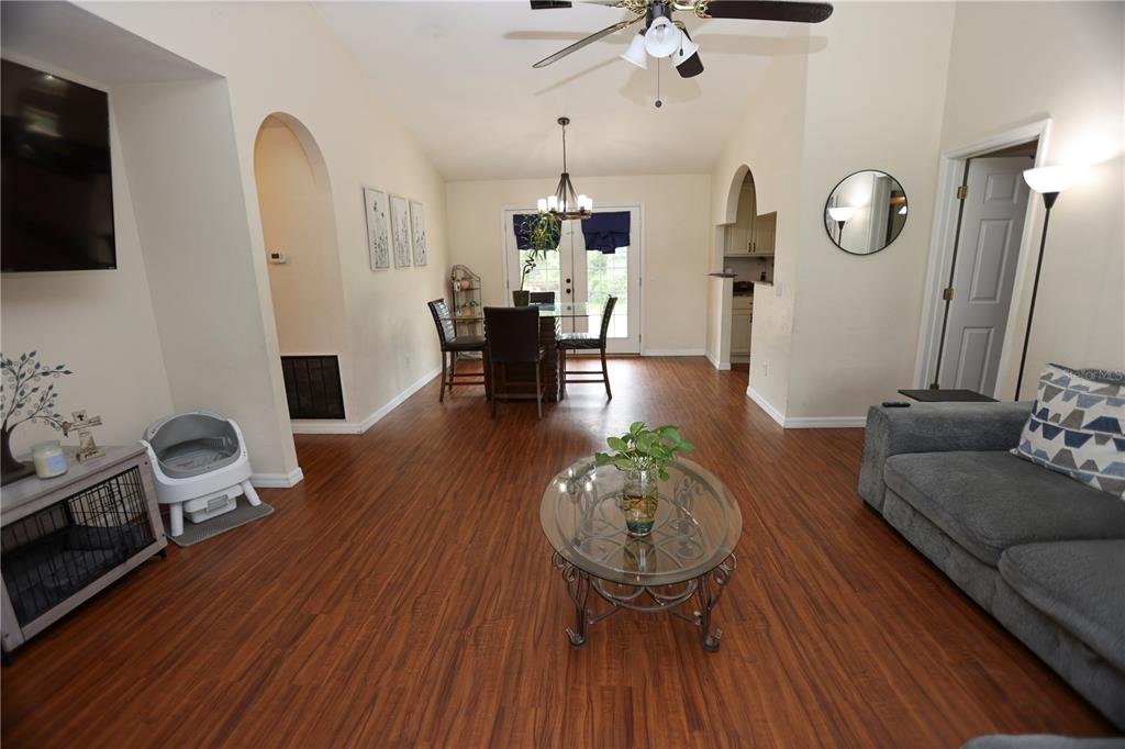 An open-concept living and dining area features wood-look flooring, a ceiling fan, and glass doors — 1302 MAYRA ROAD SW, LIVE OAK, FL