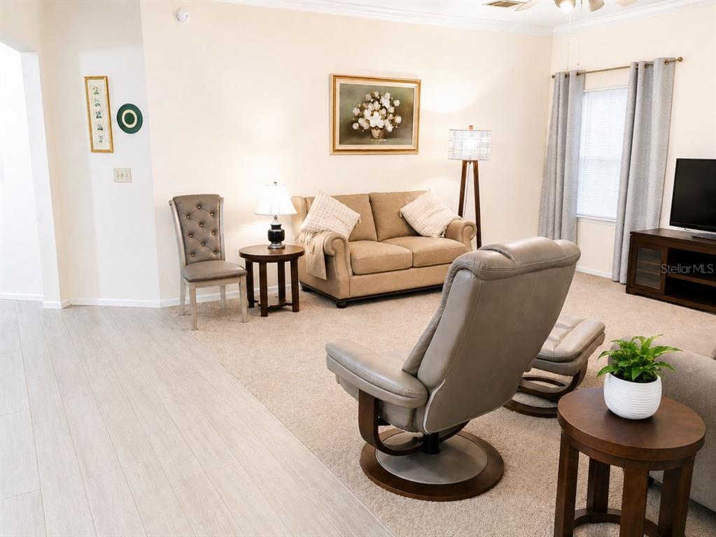 A living room features a beige sofa, a gray recliner, and a side table — 143 VILLA DI ESTE TERRACE UNIT 105, LAKE MARY, FL