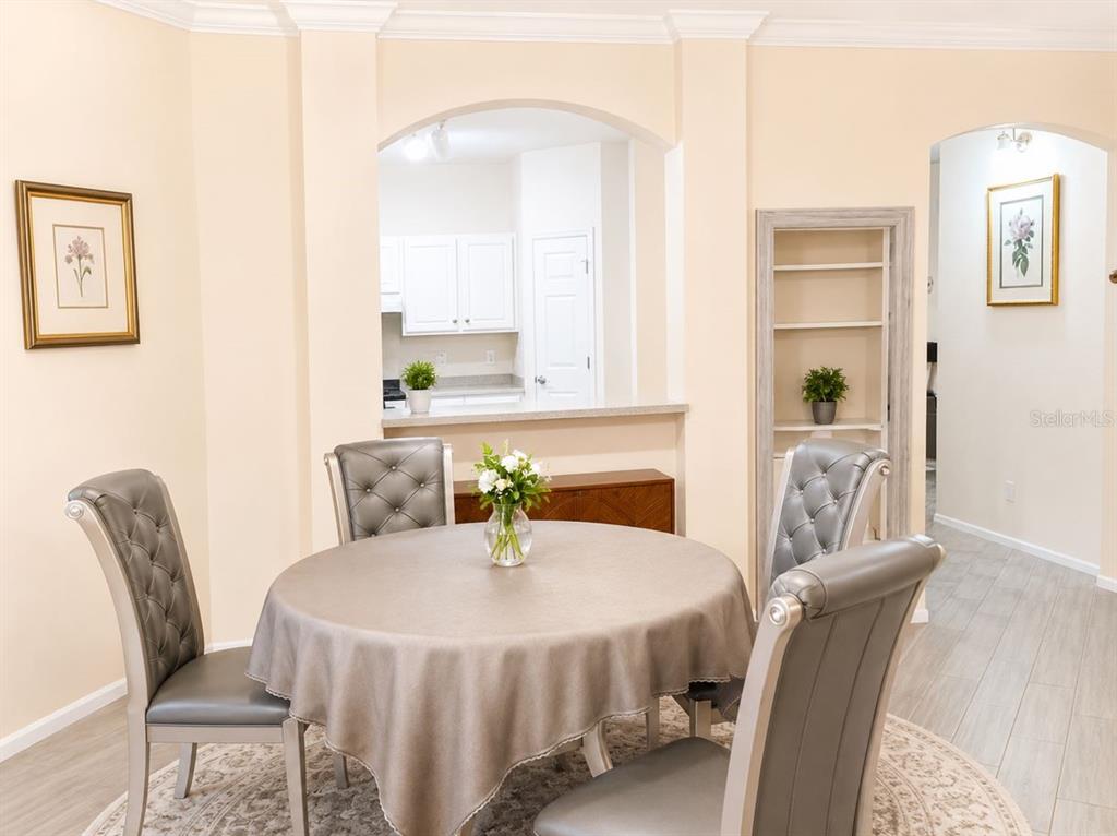 A dining area features a round table with grey chairs, an arched opening, and shelving — 143 VILLA DI ESTE TERRACE UNIT 105, LAKE MARY, FL