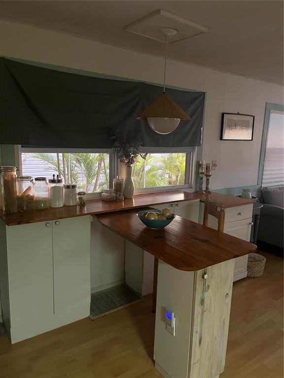 A kitchen features a wooden breakfast bar, white cabinets, and a hanging pendant light — 34188 CANAL DRIVE N, PINELLAS PARK, FL