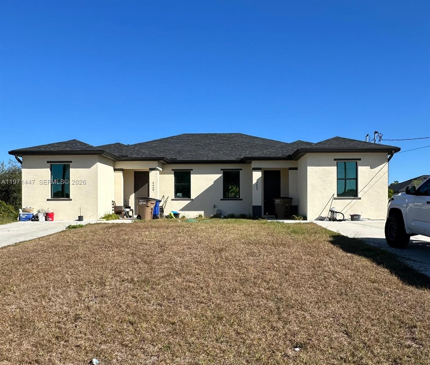 A single-story duplex with a tan stucco exterior, dark trim, and a dark shingled roof — 4662 SW 26th st # 4662, Lehigh Acres FL 33973, LEHIGH ACRES, FL