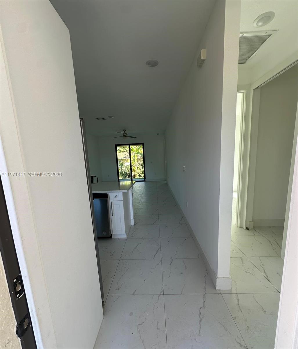 A hallway with white marble-style tile floors leads toward a kitchen and a glass door — 4662 SW 26th st # 4662, Lehigh Acres FL 33973, LEHIGH ACRES, FL