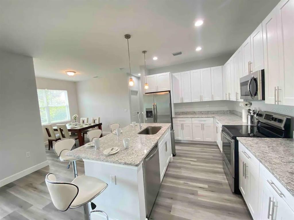 A kitchen features white cabinets, granite countertops, stainless steel appliances, and a central island — 14257 IMLAY AVENUE, PORT CHARLOTTE, FL