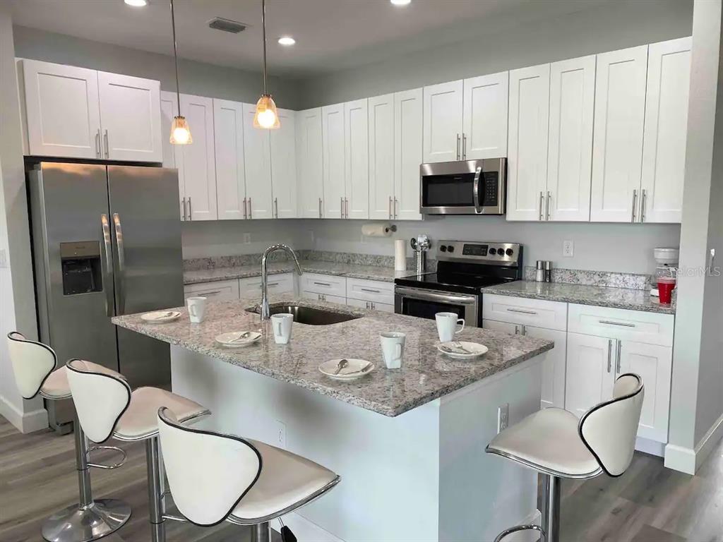 A kitchen with white cabinets, granite countertops, a center island, and stainless steel appliances — 14257 IMLAY AVENUE, PORT CHARLOTTE, FL