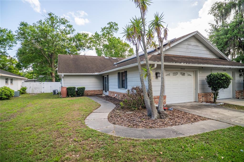 A single-story house with a white garage, gray siding, and a curved concrete walkway — 7802 RICHWOOD DRIVE, ORLANDO, FL