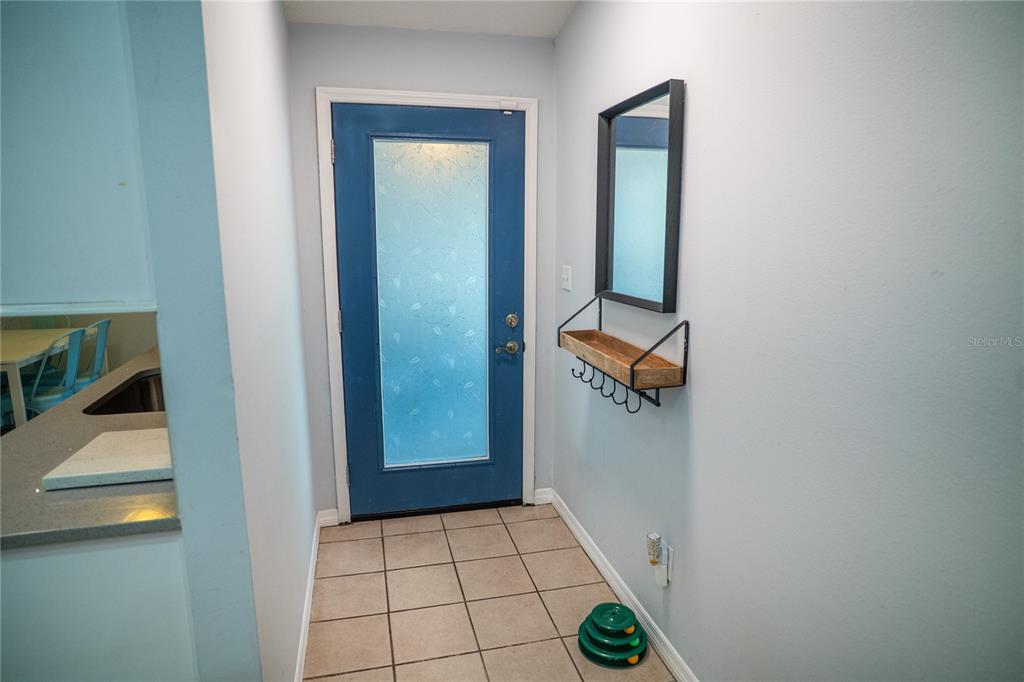An entryway features a blue door with a frosted glass panel and a wall-mounted shelf — 7802 RICHWOOD DRIVE, ORLANDO, FL