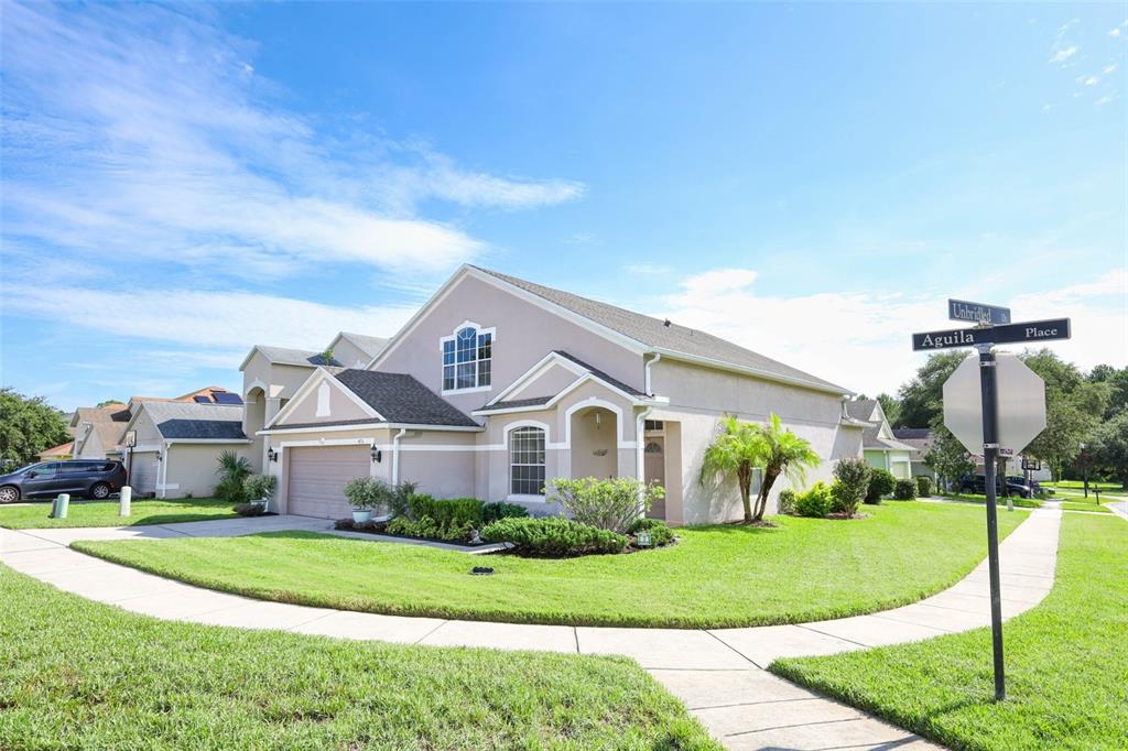 A beige two-story suburban house with a garage and a corner street sign — 4715 AGUILA PLACE, ORLANDO, FL