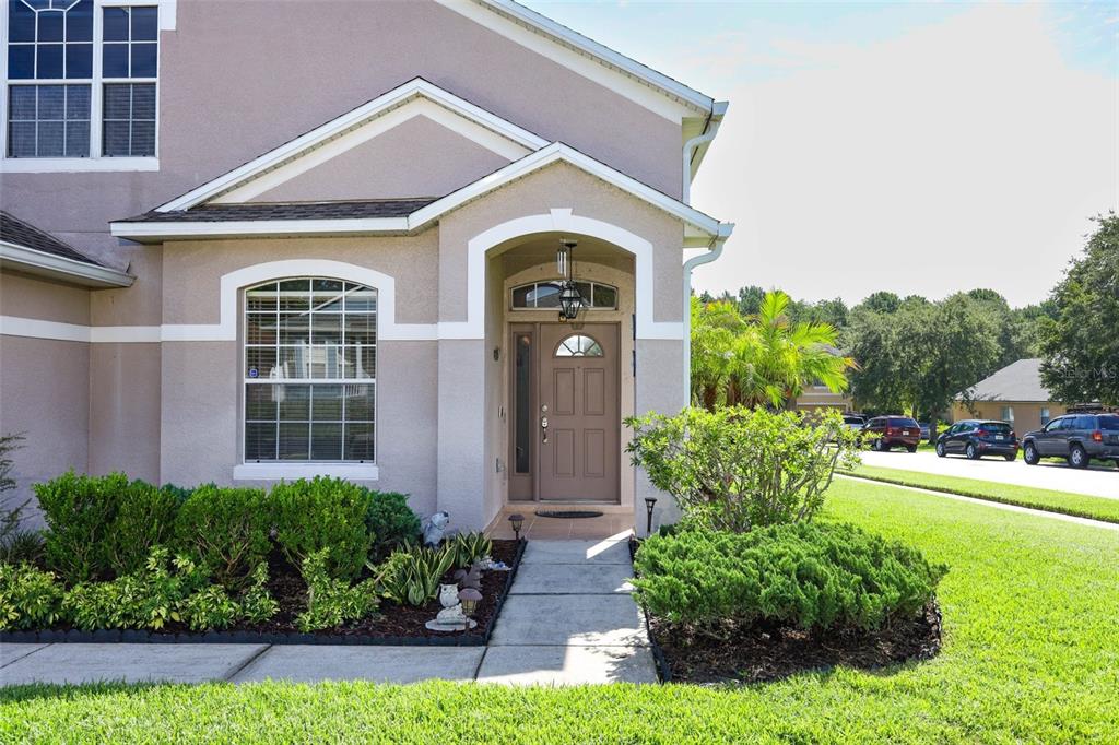 The exterior of a tan house features a covered entryway with a brown front door — 4715 AGUILA PLACE, ORLANDO, FL